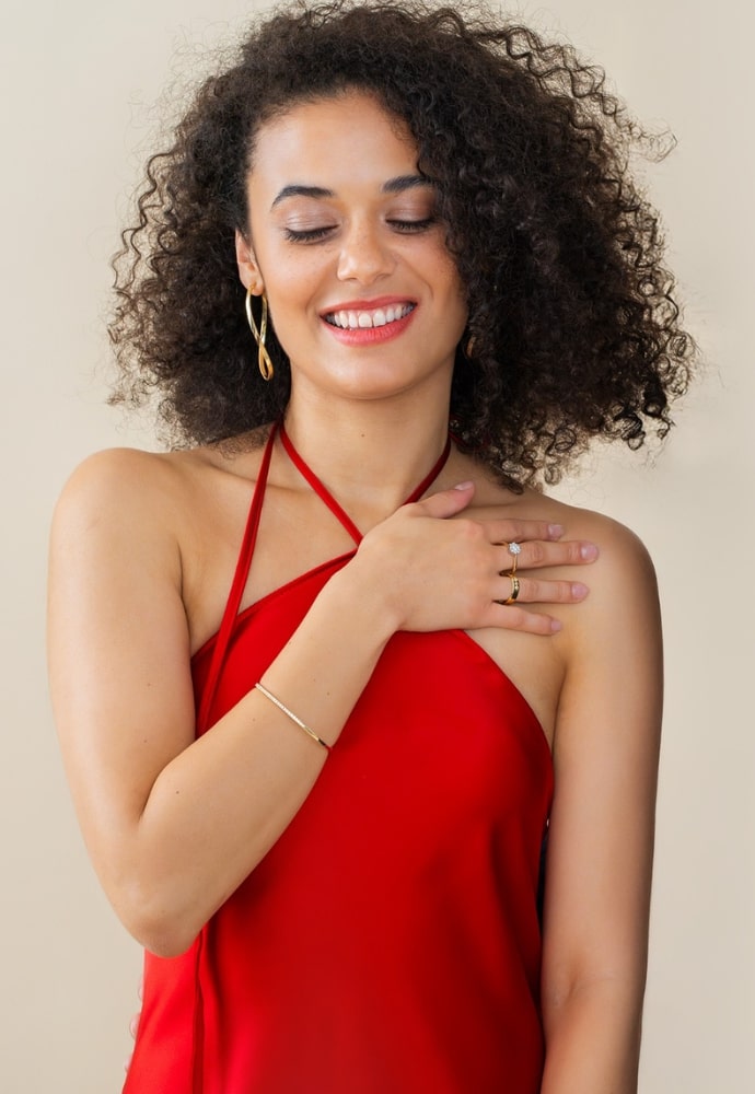 Kobieta w czerwonej sukience z wyraźną złotą biżuterią z cyrkoniami