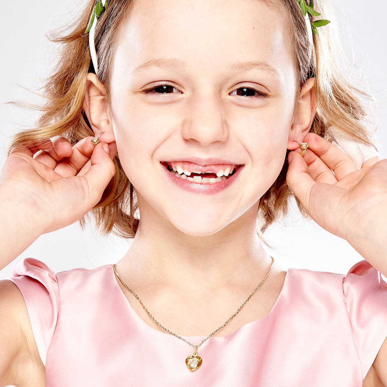 Dziewczynka w sukience ze złotymi kolczykami i złotym medalikiem 585