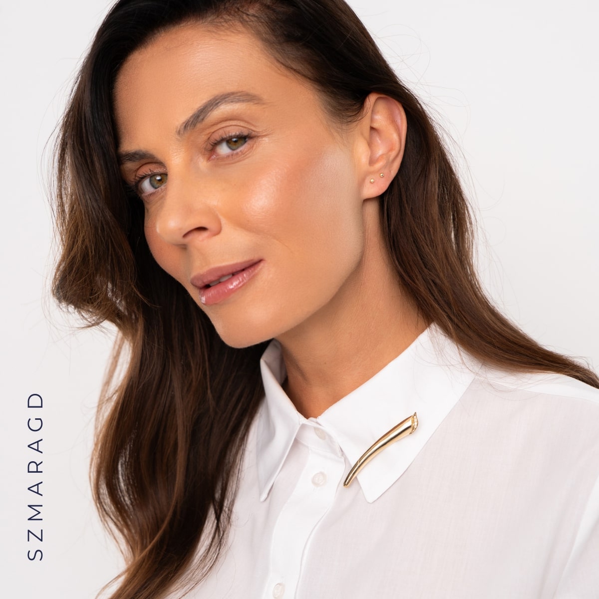 Kobieta z białej koszuli ze złotą broszką ze szmaragdami