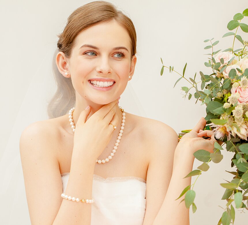 Panna młoda z biżuterią ślubną z perłami z bukietem kwiatów