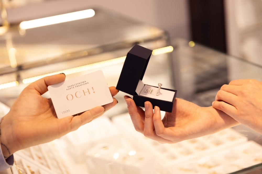 Para w salonie jubilerskim z zaręczynową kartą premiową i pierścionkiem zaręczynowym