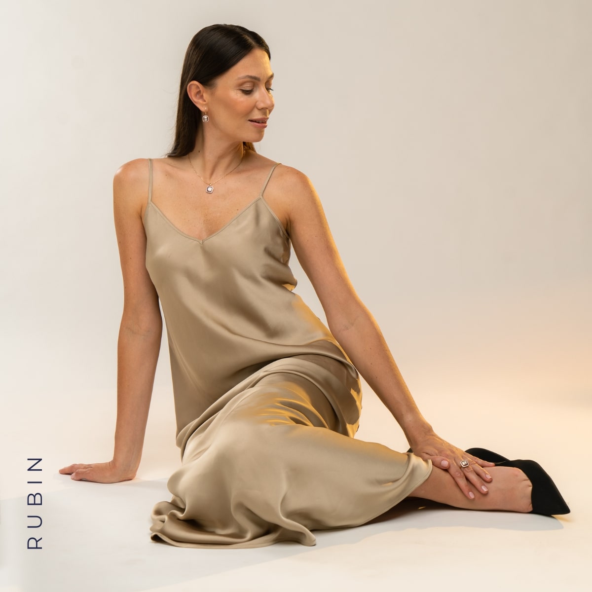 Kobieta w beżowej sukience ze złotą biżuterią z rubinami