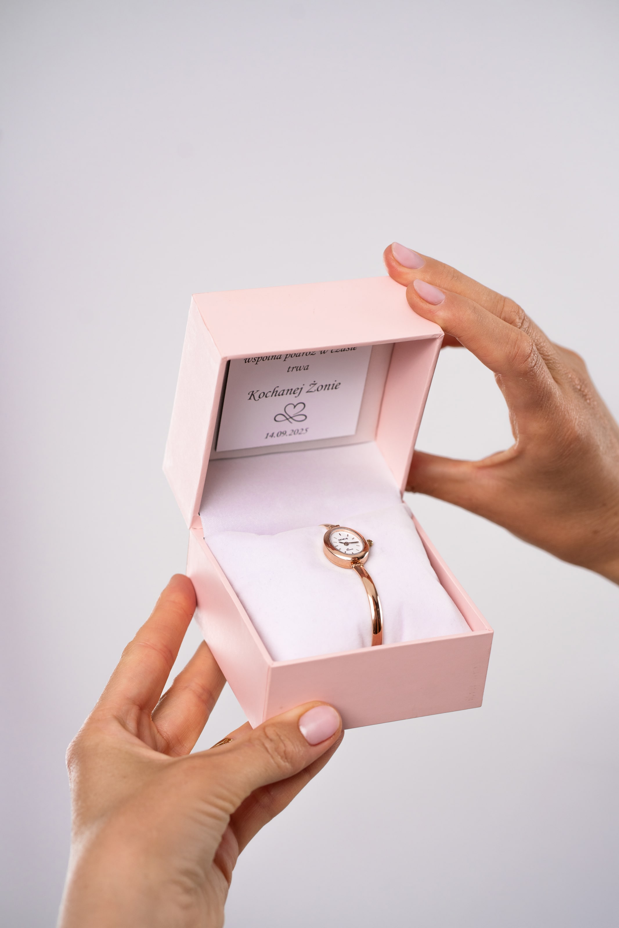 Zegarek z różowego złota z tabliczką z grawerem w rękach kobiety